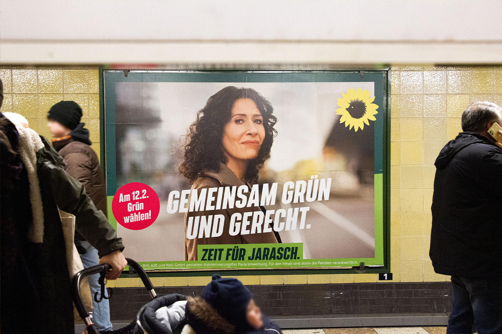 Eine Großfläche an einem Ubahn-Gleis in Berlin. Auf dem Plakat ist Bettina Jarasch zu sehen, Blick in die Kamera. Darunter steht mittig die Headline: `Gemeinsam grün und gerecht` darunter sitzt der Claim `Zeit für Jarasch.` Im Vordergrund sind Menschen zu sehen, die links und rechts am Plakat stehen.